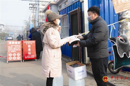 图为市民赵春兴向煤医里社区书记刘蕊捐赠口罩和消毒液.